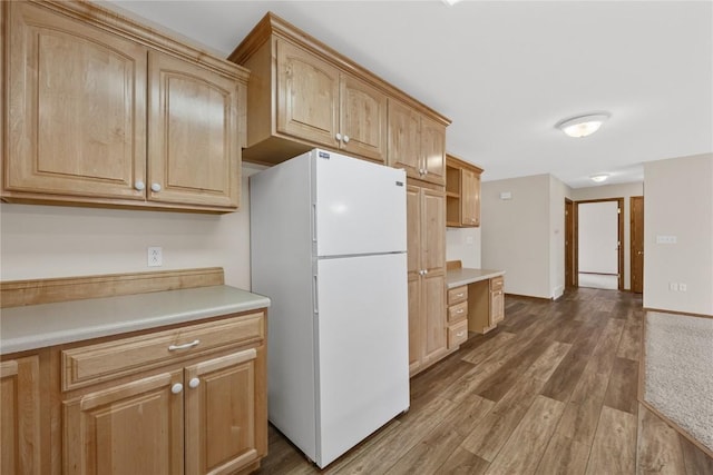 kitchen with white refrigerator, light brown cabinets, and hardwood / wood-style flooring