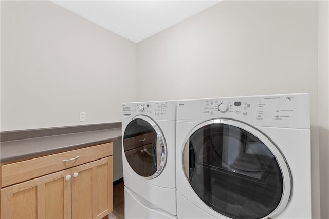 washroom featuring tile patterned flooring, washer and clothes dryer, and cabinets