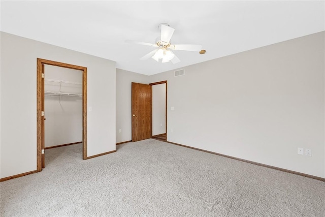 unfurnished bedroom featuring ceiling fan, a closet, a spacious closet, and light carpet