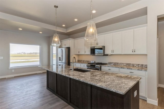 kitchen featuring stainless steel appliances, a kitchen island with sink, sink, and white cabinets