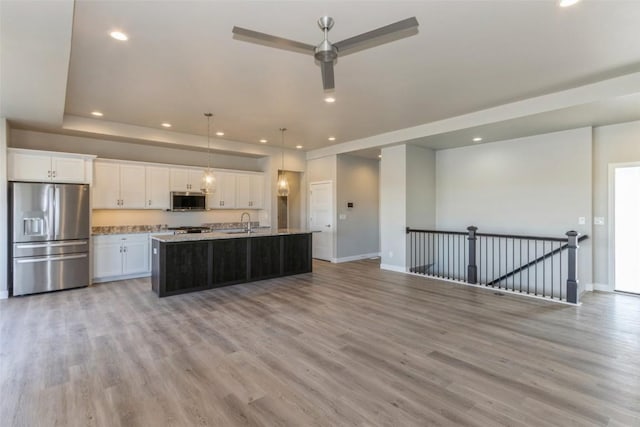 kitchen featuring sink, light hardwood / wood-style flooring, appliances with stainless steel finishes, an island with sink, and white cabinets