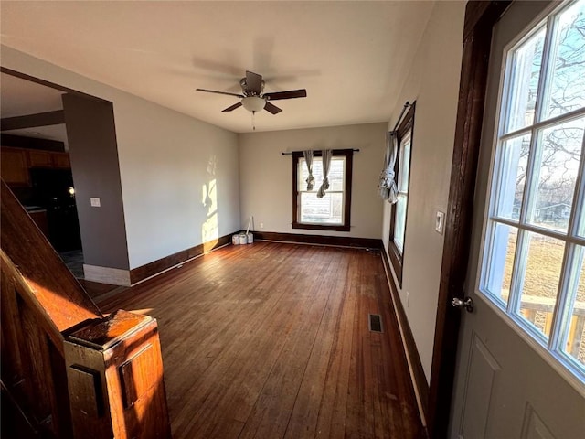 1609 11th Ave, Belle Plaine, IA 52208 - unfurnished living room with baseboards, ceiling fan, dark wood-type flooring, and visible vents