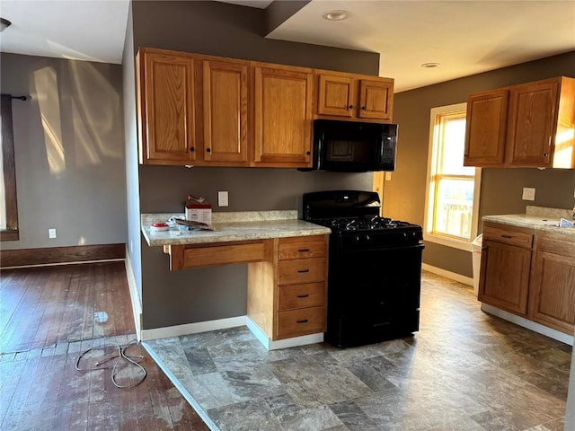 1609 11th Ave, Belle Plaine, IA 52208 - kitchen with wood finished floors, baseboards, light countertops, brown cabinets, and black appliances