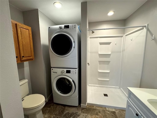 1609 11th Ave, Belle Plaine, IA 52208 - bathroom with toilet, stacked washing maching and dryer, stone finish floor, baseboards, and a stall shower