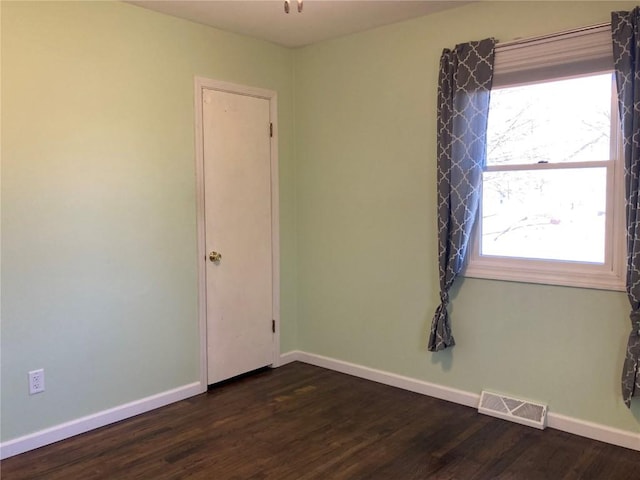 spare room featuring dark wood-type flooring and plenty of natural light