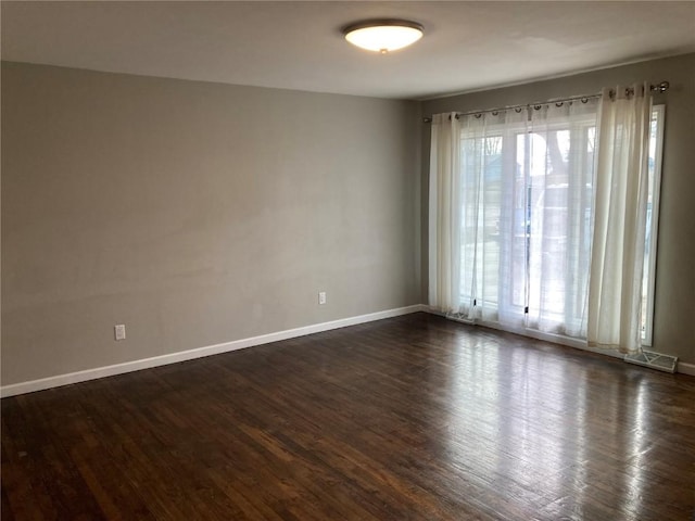 spare room with dark hardwood / wood-style flooring and plenty of natural light