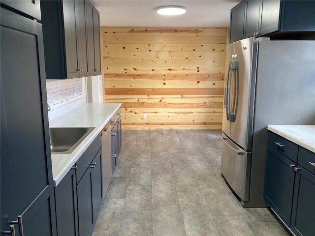 kitchen featuring wooden walls, stainless steel fridge, and sink