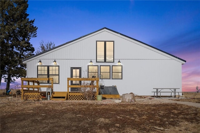 back house at dusk with a wooden deck