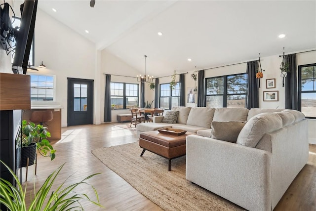 living room with high vaulted ceiling, a chandelier, and light hardwood / wood-style floors