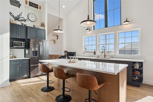 kitchen featuring sink, a center island, light wood-type flooring, pendant lighting, and stainless steel appliances