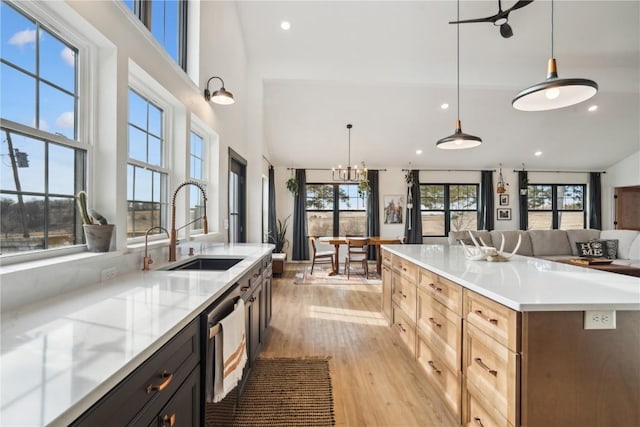 kitchen featuring pendant lighting, sink, dishwasher, light hardwood / wood-style floors, and light brown cabinetry