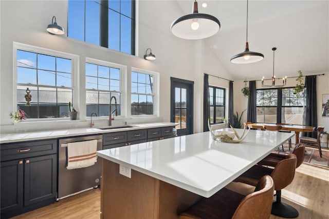 kitchen with a kitchen island, pendant lighting, dishwasher, sink, and light wood-type flooring