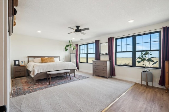 bedroom featuring ceiling fan, light hardwood / wood-style floors, and a textured ceiling