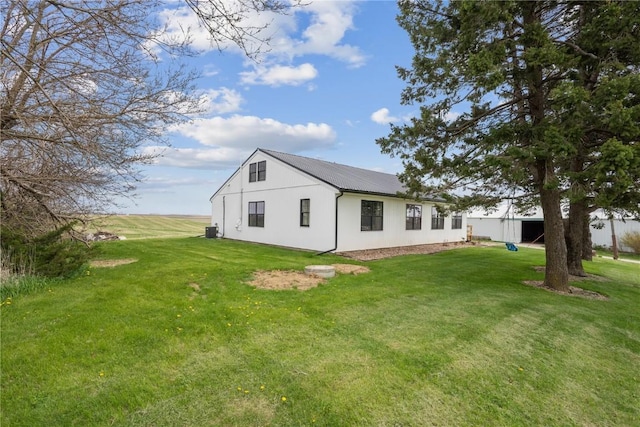 rear view of house featuring a lawn, central AC, and metal roof