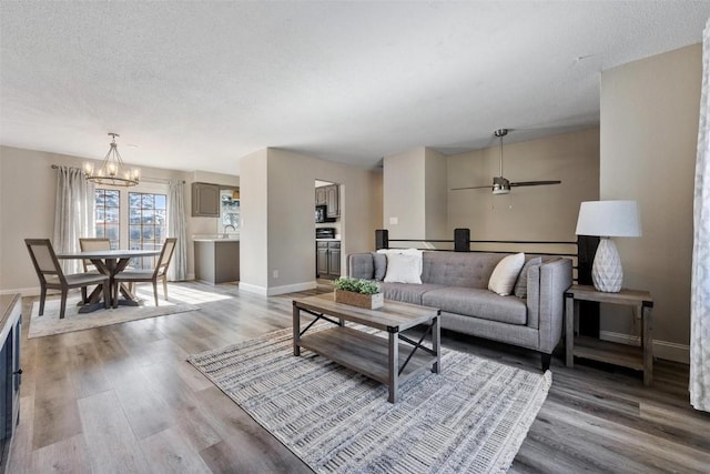 living room featuring hardwood / wood-style flooring, sink, a chandelier, and a textured ceiling