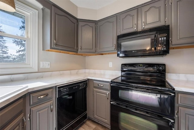 kitchen featuring gray cabinets, light hardwood / wood-style flooring, and black appliances