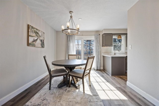 dining space with a notable chandelier, light hardwood / wood-style flooring, and a textured ceiling