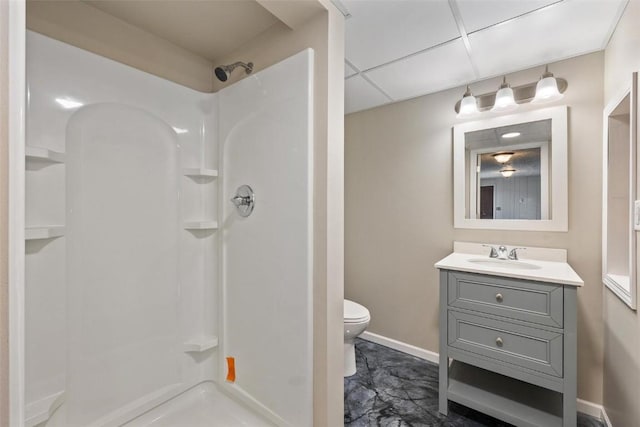 bathroom with a paneled ceiling, vanity, toilet, and a shower