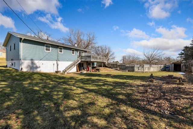 back of house with a shed, a wooden deck, a lawn, and an outdoor fire pit