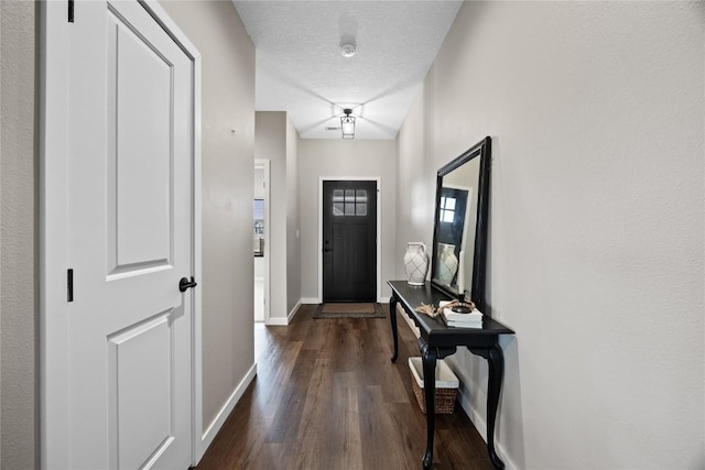 doorway to outside with dark wood-type flooring and a textured ceiling