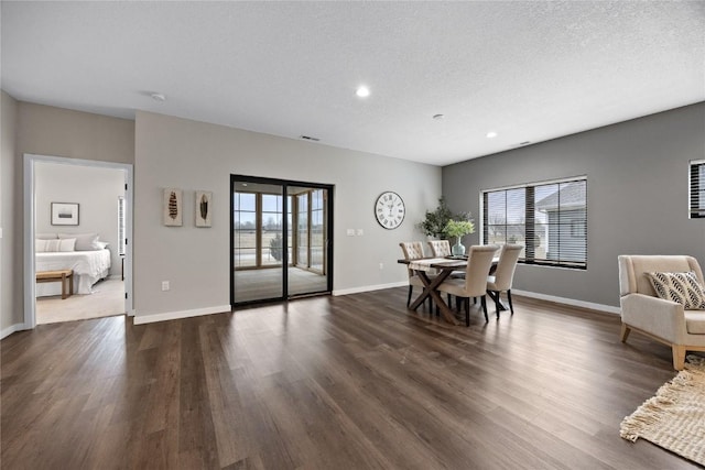 dining room with a textured ceiling, dark hardwood / wood-style floors, and a healthy amount of sunlight