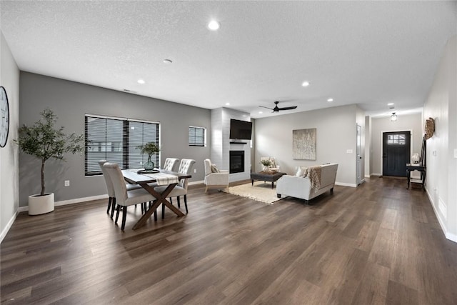 dining space featuring dark hardwood / wood-style flooring, ceiling fan, a textured ceiling, and a fireplace