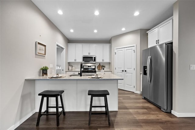 kitchen with stainless steel appliances, a breakfast bar area, white cabinets, and kitchen peninsula