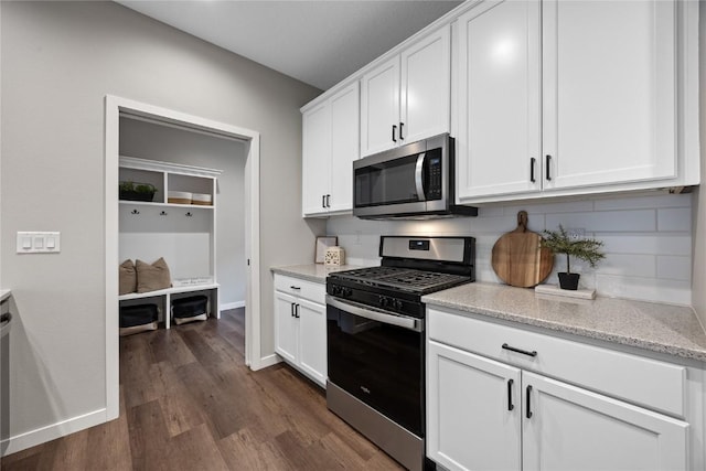 kitchen featuring dark wood-type flooring, white cabinetry, tasteful backsplash, appliances with stainless steel finishes, and light stone countertops