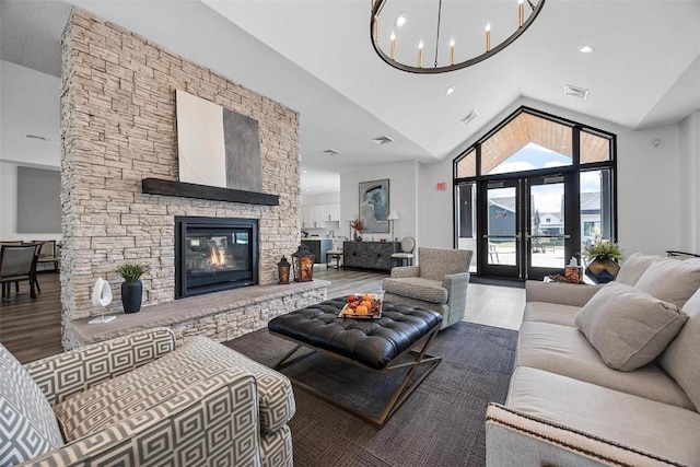 living room with high vaulted ceiling, a fireplace, wood-type flooring, a chandelier, and french doors