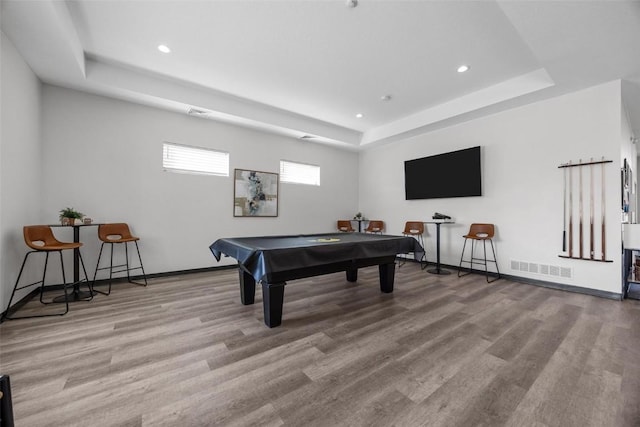 game room with billiards, a tray ceiling, and light hardwood / wood-style floors