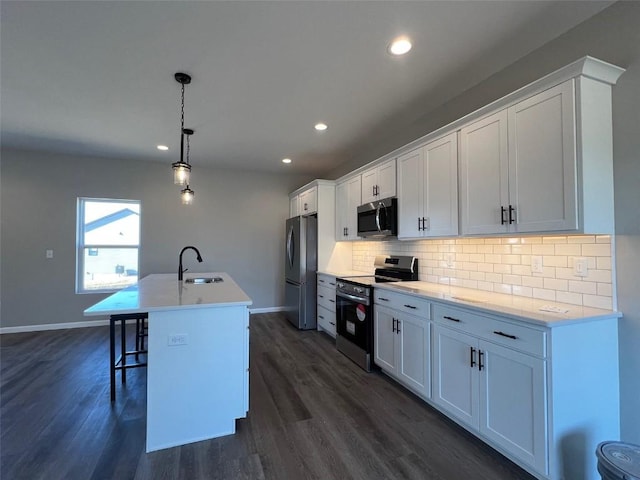 kitchen featuring pendant lighting, white cabinetry, an island with sink, decorative backsplash, and stainless steel appliances