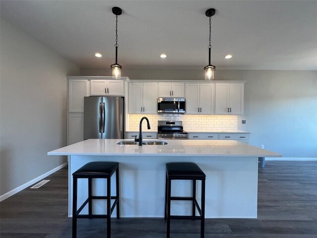 kitchen featuring white cabinets, appliances with stainless steel finishes, sink, and a kitchen island with sink