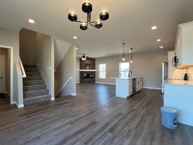 interior space with pendant lighting, dark wood-type flooring, appliances with stainless steel finishes, a fireplace, and white cabinets