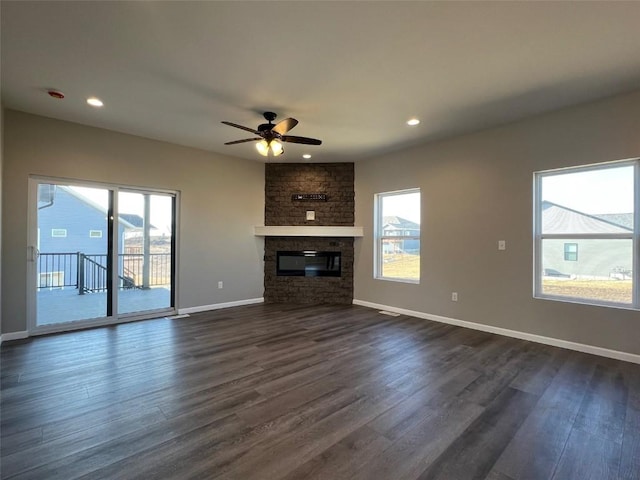 unfurnished living room featuring ceiling fan, dark wood-type flooring, and a fireplace