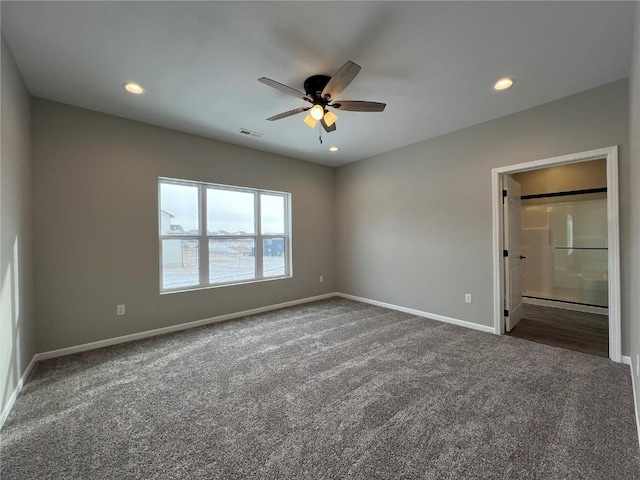 unfurnished bedroom featuring ensuite bathroom, ceiling fan, and dark carpet