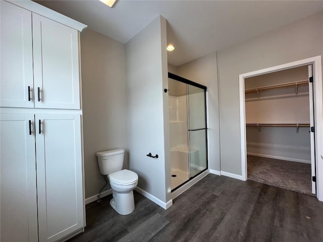 bathroom with wood-type flooring, toilet, and a shower with shower door