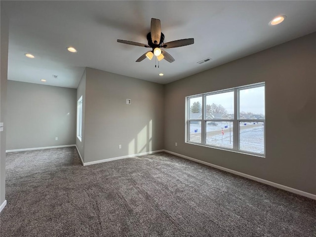 spare room with ceiling fan and dark carpet