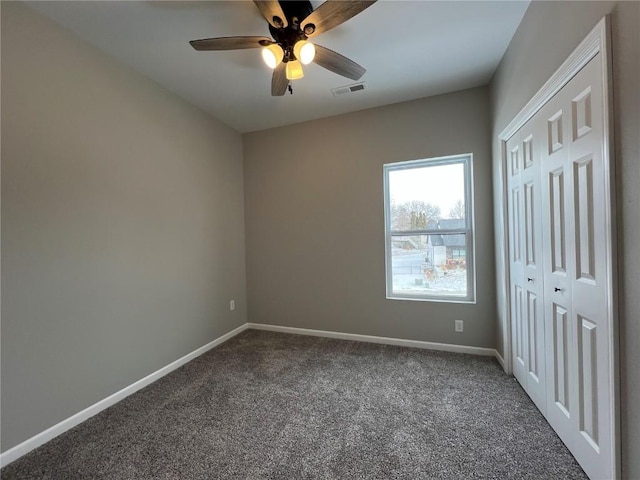 unfurnished bedroom with a closet, ceiling fan, and dark colored carpet