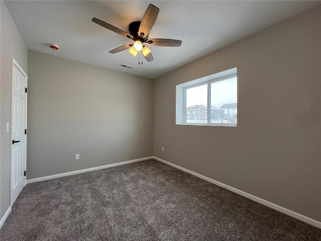 spare room with ceiling fan and dark carpet