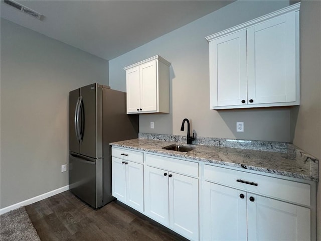 kitchen with light stone counters, dark hardwood / wood-style flooring, sink, and white cabinets