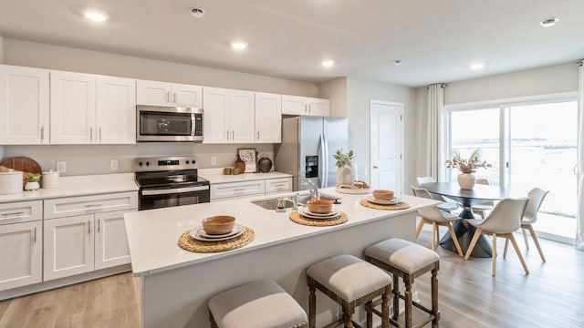 kitchen featuring white cabinetry, appliances with stainless steel finishes, sink, and an island with sink