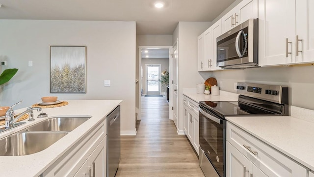 kitchen featuring white cabinetry, appliances with stainless steel finishes, sink, and light hardwood / wood-style flooring