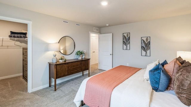 carpeted bedroom featuring a walk in closet and a closet