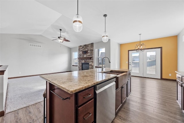 kitchen featuring a fireplace, sink, hanging light fixtures, a kitchen island with sink, and stainless steel dishwasher