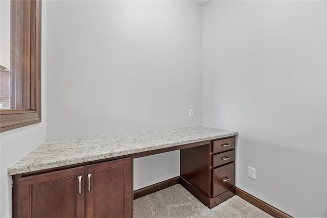 unfurnished office with light colored carpet and built in desk