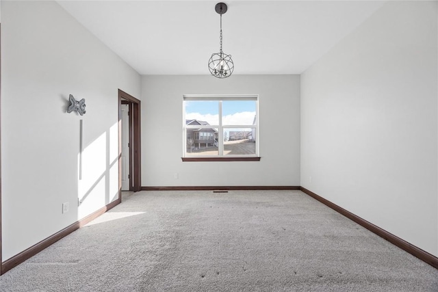 empty room featuring light carpet and a notable chandelier