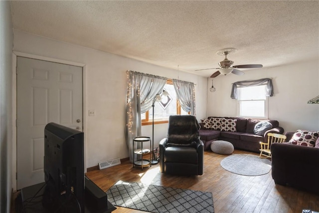 living room with hardwood / wood-style flooring, ceiling fan, and a textured ceiling