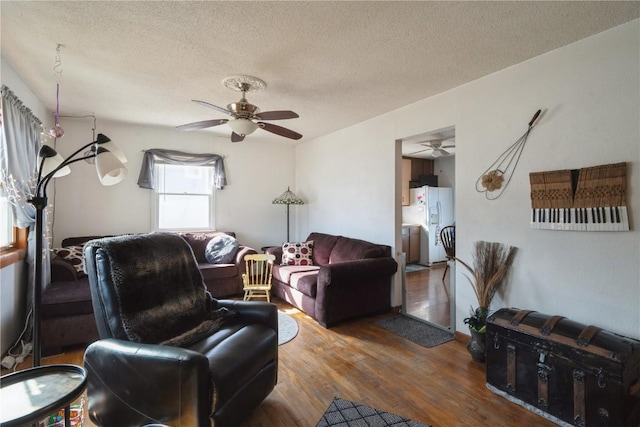 living room featuring ceiling fan, hardwood / wood-style floors, and a textured ceiling