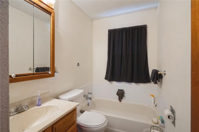 bathroom with vanity, a washtub, toilet, and a textured ceiling