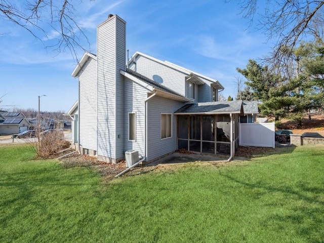 rear view of property with a sunroom, central AC, and a lawn